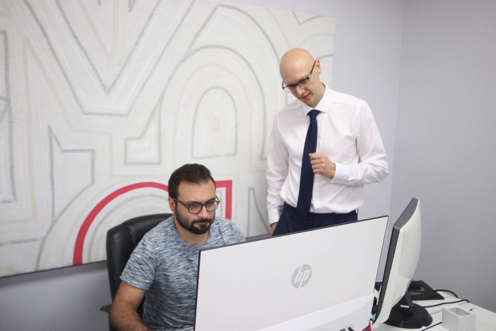 Moe beside a colleague at a desk